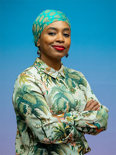 Half-portrait of Najla Ahmed in a palm tree shirt and a turquoise head scarf